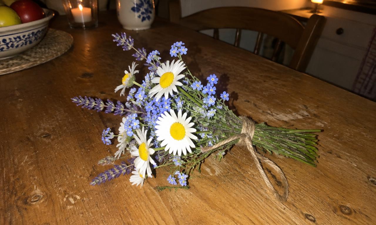 Un petit bouquet de fleurs des champs, posé sur une table en bois par une soirée tranquille.